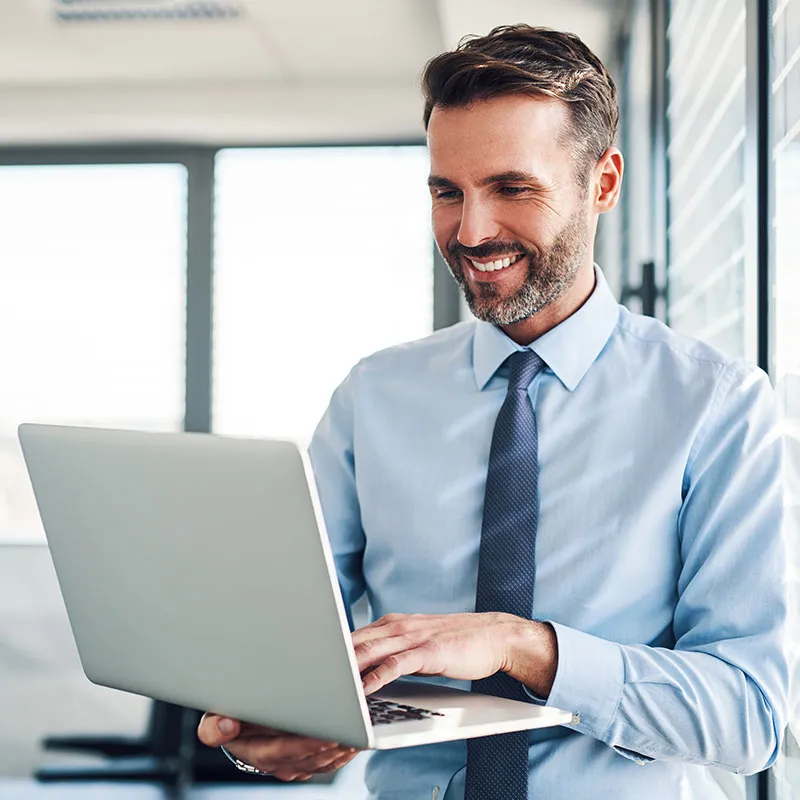 Manager in an office smiling at a laptop